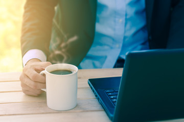Businessman relaxing by coffee cup while working.
