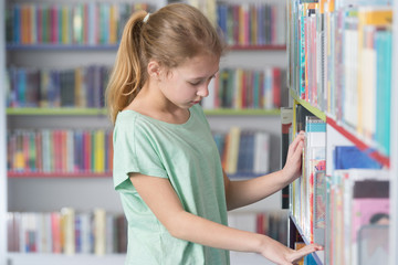 Cute girl reading book in library 

