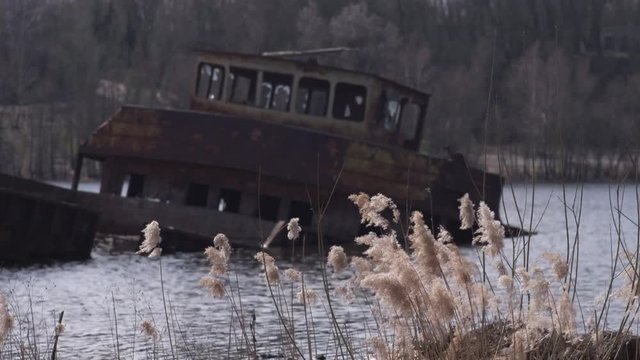 Graveyard of ships on the river.  Many rusty barges and boats in water. Chernobyl zone of alienation