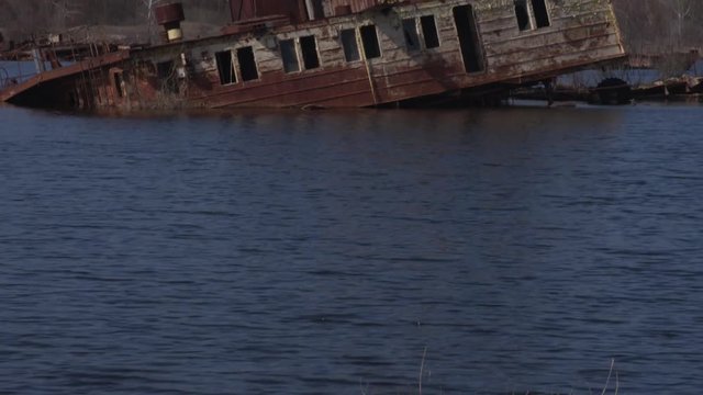 Graveyard of ships on the river.  Many rusty barges and boats in water. Chernobyl zone of alienation