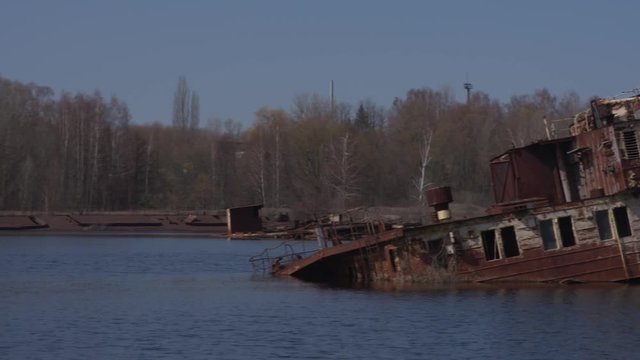 Graveyard of ships on the river.  Many rusty barges and boats in water. Chernobyl zone of alienation