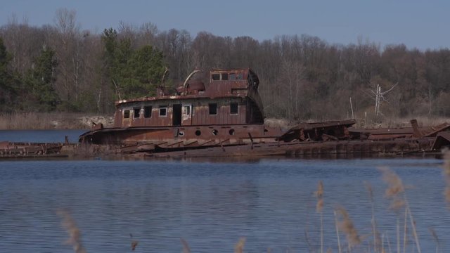 Graveyard of ships on the river.  Many rusty barges and boats in water. Chernobyl zone of alienation