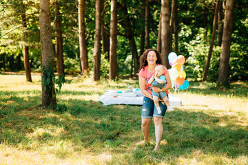 Fototapeta premium Young mother with little son having fun outdoors at picnic in the park