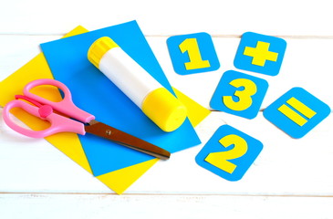 Handmade paper cards with numbers, scissors, paper sheets, glue on a white background