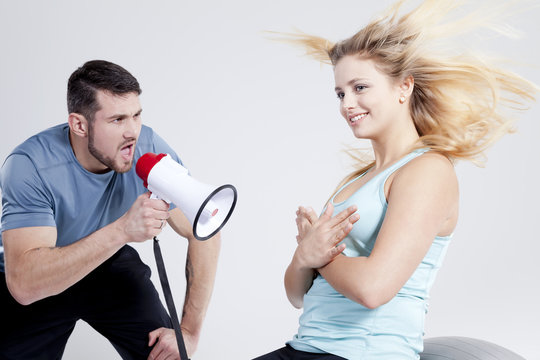 Trainer motiviert mit Megafon die Sportlerin bei Sportübung mit fliegenden Haaren Porträt