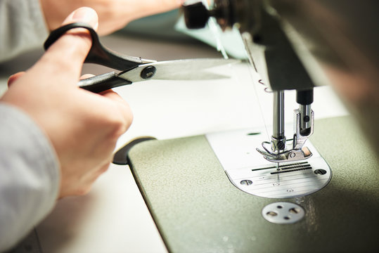 Hand cuts the thread on the sewing machine