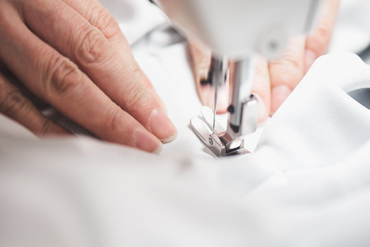 Hands sews clothes on a sewing machine