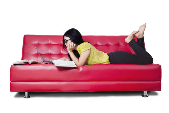 Female learner studying and reads books on sofa