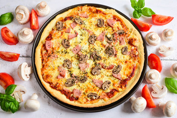 Delicious pizza with mushrooms, ham and basil.