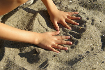 Young boy playing in the sand at the beach on a sunny summer day. 