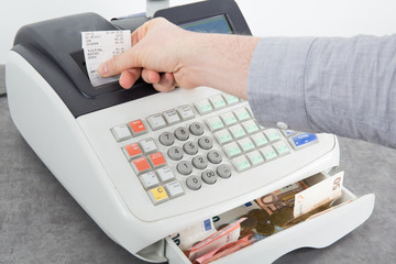 Sales person entering amount on cash register in retail store