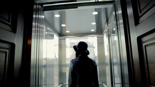 The young lady is entering the empty elevator