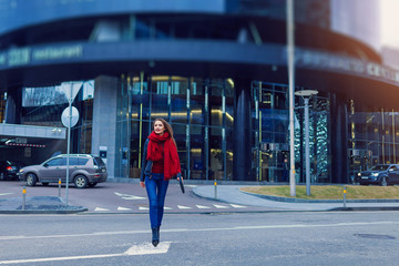 Fashion shot of pretty young woman over city background, wearing red scarf. City lifestyle. Female fashion