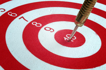 Dart arrow hitting in the target center of dartboard