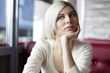 Pensive and thoughtful young woman at cafe