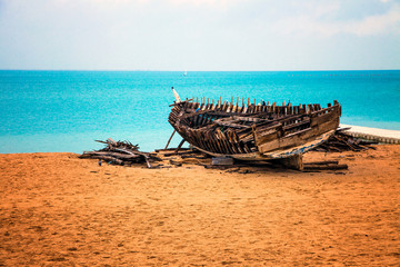 Wooden boat in decay by the sea, on the beach