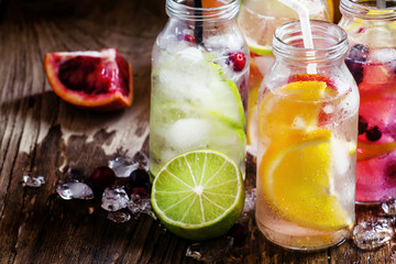 Fototapeta na wymiar Refreshing lemonades with citrus fruits and ice, vintage dark wo