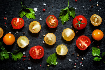 Food background: red, yellow and orange cherry tomatoes, black b