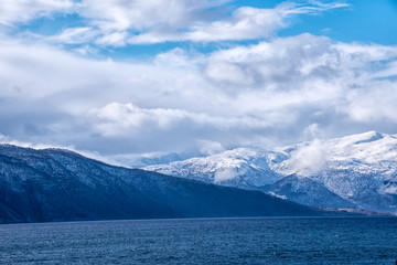 Snow caped mountain range in Norway under a blue cloudy sky