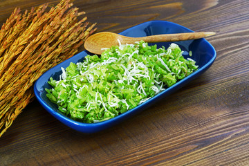 Traditional thai dessert,Pounded unripe rice with shredded rice grain with coconut on wood table.Select focus