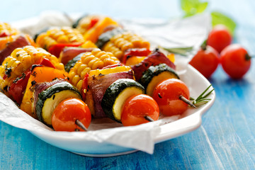 Grilled vegetarian skewers with zucchini, onion, bell pepper, corn and cherry tomatoes in a herb...