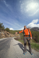 A man with a backpack on the road traveling.
