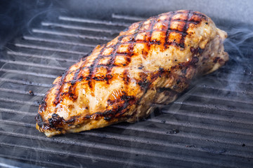 Grilled chicken breast in different variations with cherry tomatoes, .mushrooms, herbs, cut lemon on a wooden board or teflon pan. Traditional cuisine. Grill kitchen.