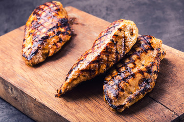 Grilled chicken breast in different variations with cherry tomatoes, .mushrooms, herbs, cut lemon on a wooden board or teflon pan. Traditional cuisine. Grill kitchen.