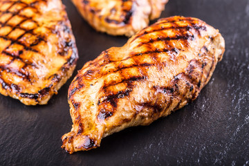 Grilled chicken breast in different variations with cherry tomatoes, .mushrooms, herbs, cut lemon on a wooden board or teflon pan. Traditional cuisine. Grill kitchen.