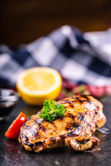Grilled chicken breast in different variations with cherry tomatoes, .mushrooms, herbs, cut lemon on a wooden board or teflon pan. Traditional cuisine. Grill kitchen.