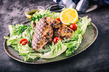 Grilled chicken breast in different variations with lettuce salad cherry tomatoes .mushrooms herbs cut lemon on a wooden board or teflon pan. Traditional cuisine. Grill kitchen.