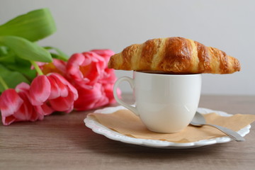 cup of cappuccino and yummy croissant with flowers