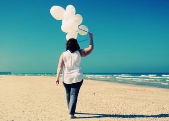 woman holding white balloons on seaside