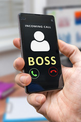 Man in office holds smartphone with incoming call from boss.