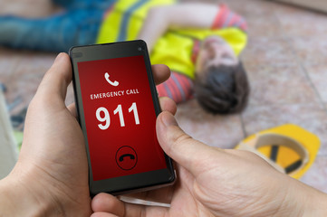 Man dialing emergency (911 number) on smartphone. Injured worker had accident and is lying on the floor.