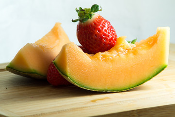 Fragola e melone in primo piano, sfondo bianco