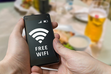 Man holds smartphone and is using free wifi in restaurant.