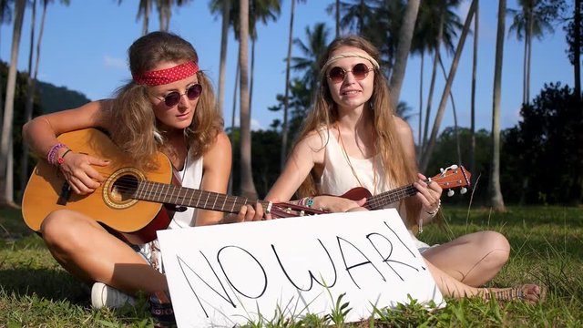 Young Hippie Women Playing Guitar with No War Sign in Grass