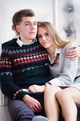 Couple of teenagers sitting against mirror wall