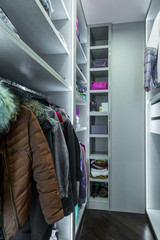 Clothes hanging on rail in white wardrobe