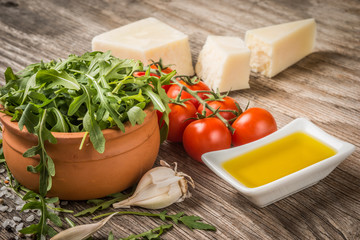 Arugula tomatoes cheese and oil on rustic table