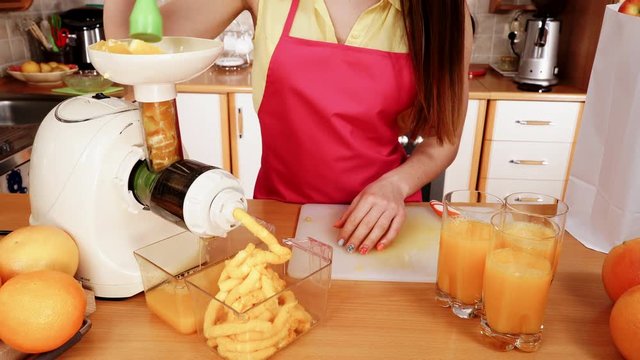 Woman making orange juice in juicer machine 4K