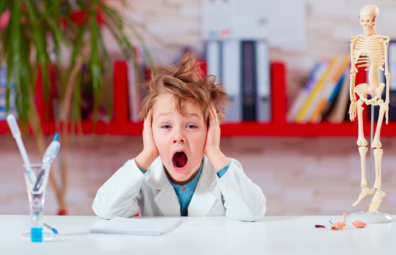young kid, schoolboy yawning during experiment in school lab