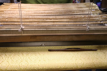 Close up of gold silk weaving on loom