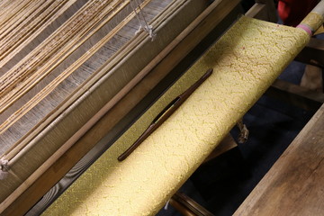 Close up of gold silk weaving on loom