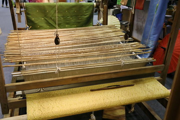 Close up of gold silk weaving on loom