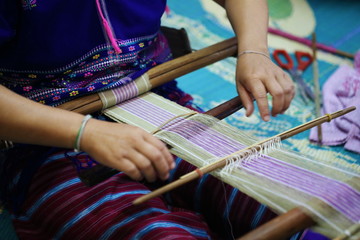 woman weaving blue and white pattern on loom, hill tribe culture