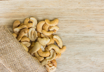 raw cashew nuts pour from sack on wood
