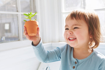  Happy toddler girl playing with potted plants