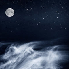 Black and White Clouds and Moon with stars at night. Image has a pleasing paper grain and texture when viewed at 100 percent.